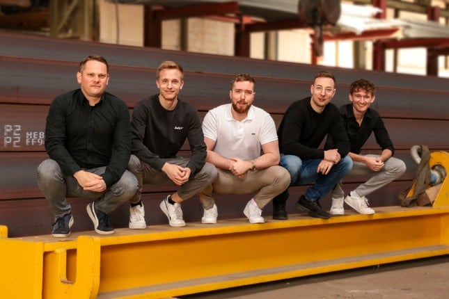 Teamfoto BIGBOXX hockend in der Stahlbauhalle
